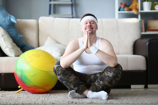Calm young man enjoying meditation at home. Yoga and meditation concept