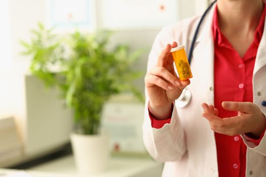 Doctor holds jar of medical capsules pills in clinic. Prescribing medications by therapist