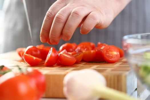 Chef cuts fresh ripe tomatoes on cutting board surrounded ingredients. Healthy eating and benefits of tomatoes concept