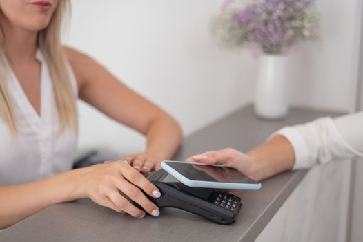A woman pays using a contactless payment of the NFC used by a smartphone