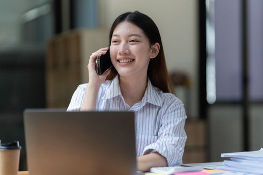 Happy Asian business woman talking with client on the cell phone.