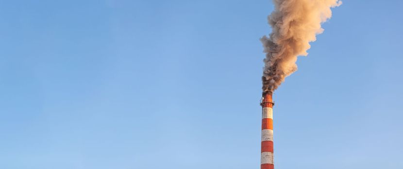 White thick smoke from the boiler room chimney. Smoke against the blue sky. Air pollution. Heating of the city. Industrial zone.