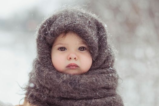 Retro photo of adorable baby in a woolen shawl in winter.