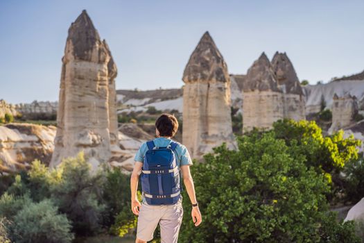 Man tourist on background of Unique geological formations in Love Valley in Cappadocia, popular travel destination in Turkey.