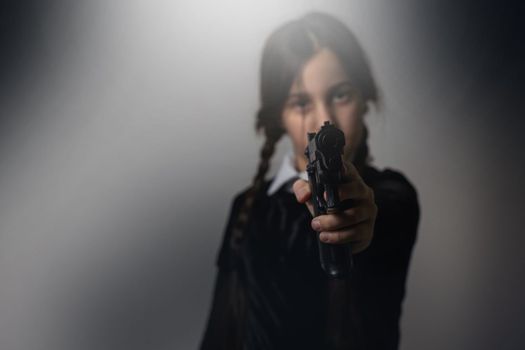 A girl with braids in a gothic style on a dark background with weapons.