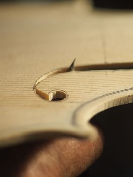 violinmaker cutting and sawing golden period cremonese violin model fholes with a blade with precision