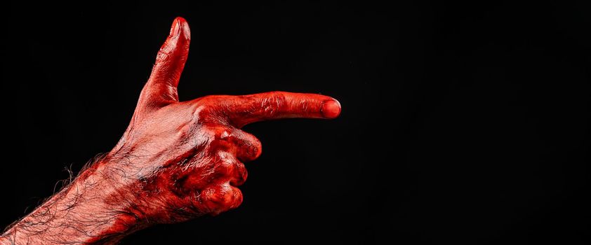 Bloody male hand gesturing shows a gun against black background