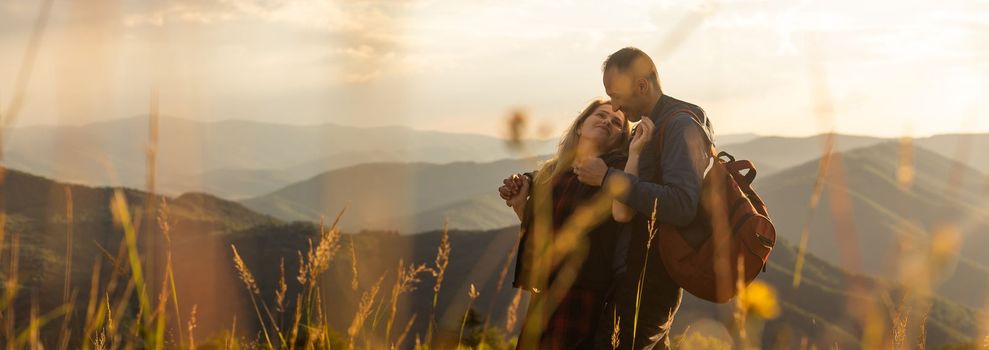 travel to mountains, tourists hikers with backpacks at sunset enjoying panoramic view.