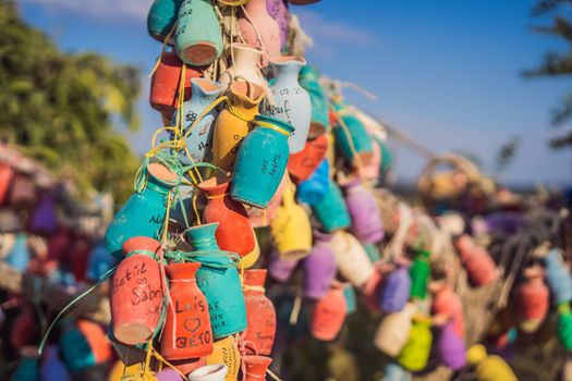 Wish tree. Small multi-colored jugs with inscriptions, wishes hanging on the branches of a tree., against the backdrop of sand ruins and blue sky.