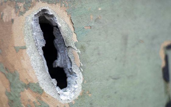 Hole or hole, armor deformation from a projectile close-up. Damaged armor of a Russian armored personnel carrier by shell fragments. War in Ukraine. Russian combat vehicle with holes in the armor