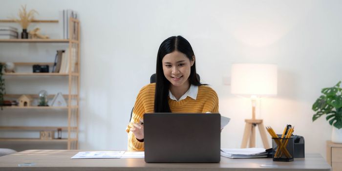 Portrait of Young Asian woman hand freelancer is working her job on computer tablet in modern home. Doing accounting analysis report real estate investment data, Financial and tax systems concept..