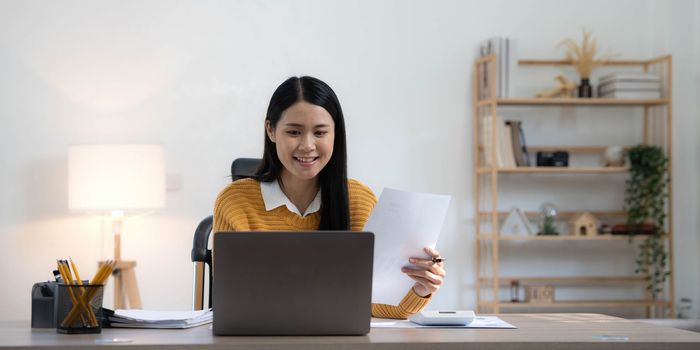 Portrait of Young Asian woman hand freelancer is working her job on computer tablet in modern home. Doing accounting analysis report real estate investment data, Financial and tax systems concept..