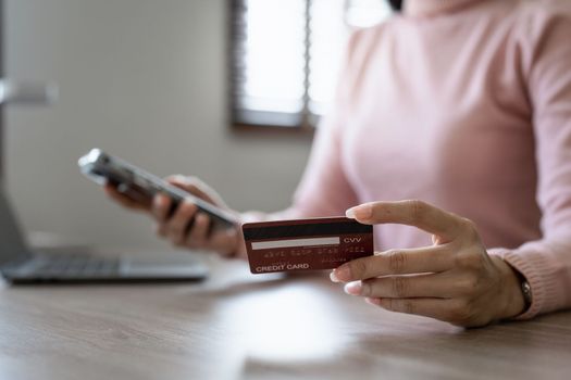 Young person using credit card and laptop computer. Online shopping, e-commerce concept.