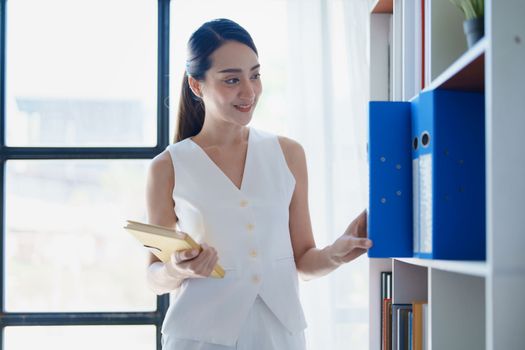 portrait of Asian female employees notebooks and pick up important documents to start their morning work