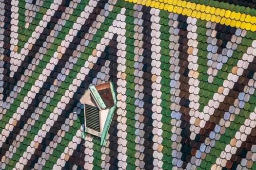 Abstract view of decorative tiling pattern with lonely window on the roof of St Stephen's Cathedral in Vienna, Austria