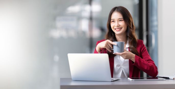 Portrait of smiling beautiful business asian woman in pink suit working in home office desk using computer. Business people employee freelance online marketing e-commerce, work from home concept..