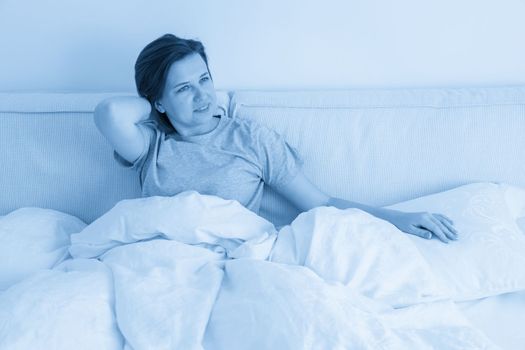 Smiling brunette woman sitting on her bed in her bedroom