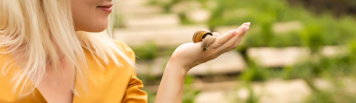 Close-up of snails on women's hand in the hothouse of a farm for growing snails