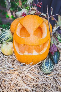 pumpkin with a face lies on a haystack for Halloween.