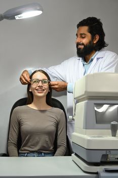 Happy caucasian woman testing new glasses with optometrist in optical store. Eyesight and vision concept.