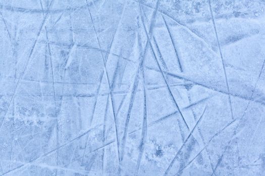 Empty ice rink with skate marks after the session outdoor. skating ice rink texture covered with snow in daylight. Close up of blue ice rink floor, copy space