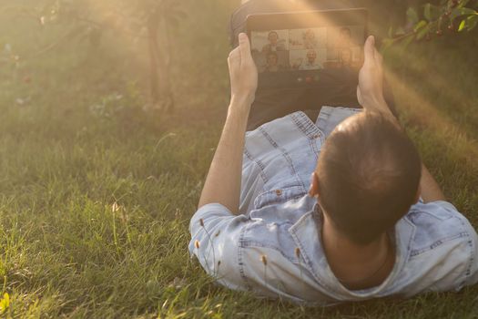 Young man in the garden in summer on the laptop computer while chatting online as a freelancer