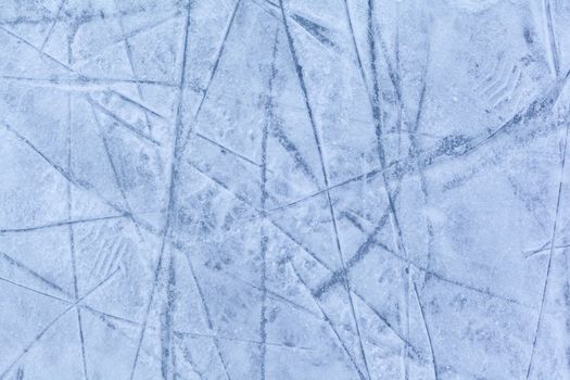 Empty ice rink with skate marks after the session outdoor. skating ice rink texture covered with snow in daylight. Close up of blue ice rink floor, copy space