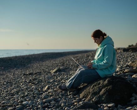 Caucasian woman working freelance on laptop on the beach