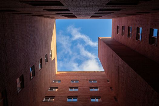 Brick high-rise new square house on a blue sky background. View from the courtyard to the top of the sky. Luxury housing and offices for work.