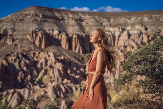 Young woman exploring valley with rock formations and fairy caves near Goreme in Cappadocia Turkey.