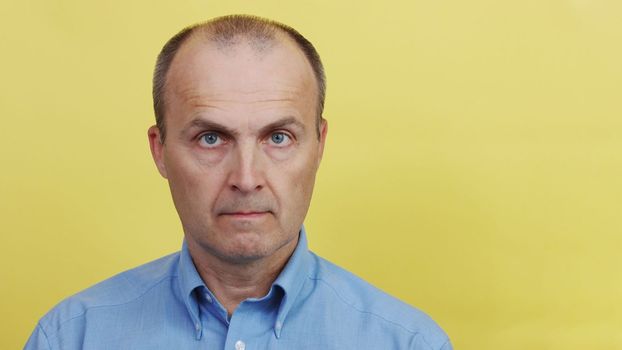 A man in a blue shirt on a yellow paper background.