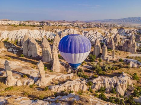 Colorful hot air balloons flying over at fairy chimneys valley in Nevsehir, Goreme, Cappadocia Turkey. Spectacular panoramic drone view of the underground city and ballooning tourism. High quality.