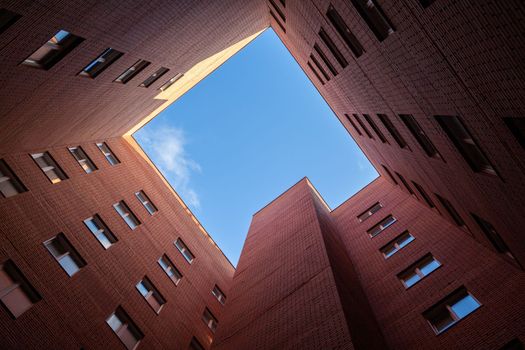 Brick high-rise new square house on a blue sky background. View from the courtyard to the top of the sky. Luxury housing and offices for work.