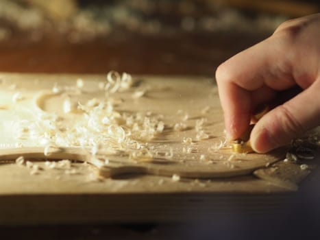 luthier working on raw wood violin plate with finger plane on the bench