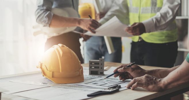 Civil engineer teams meeting working together wear worker helmets hardhat on construction site in modern city. Foreman industry project manager engineer teamwork. Asian industry professional team...