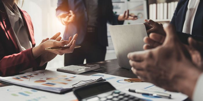 Business People Meeting using laptop computer,calculator,notebook,stock market chart paper for analysis Plans to improve quality next month. Conference Discussion Corporate Concept