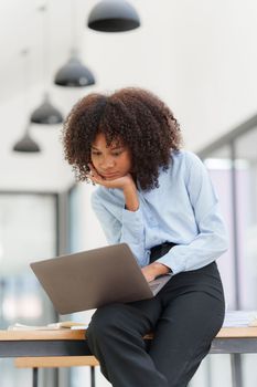 Portrait young african american businesswoman looking at laptop. Woman reading news, report or email. Online problem, finance mistake, troubleshooting.