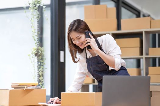Young Asian Woman Working at home, Young Owner Woman talking to customer and working with happy emotion. People with online shopping SME entrepreneur or freelance working concept...