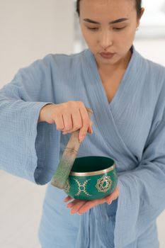 Asian woman playing Tibetan singing bowl