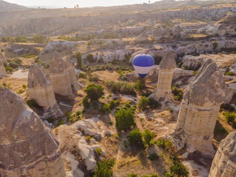 Colorful hot air balloons flying over at fairy chimneys valley in Nevsehir, Goreme, Cappadocia Turkey. Spectacular panoramic drone view of the underground city and ballooning tourism. High quality.