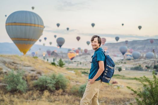 Tourist man looking at hot air balloons in Cappadocia, Turkey. Happy Travel in Turkey concept. Man on a mountain top enjoying wonderful view.