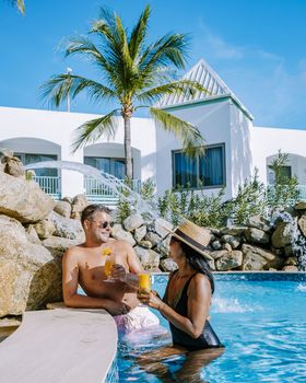 Couple in the swimming pool with cocktails during summer vacation, men and women in the swim pool