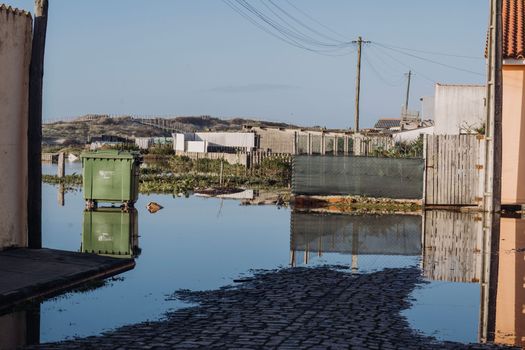 Water under Garbage disposal through street and houses after rainfall in Espinho , Portugal. January 9 2023.