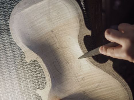 artisan maker drilling and carving on fiddle plate outline