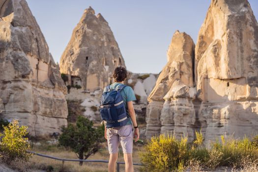 Man tourist on background of Unique geological formations in Love Valley in Cappadocia, popular travel destination in Turkey.