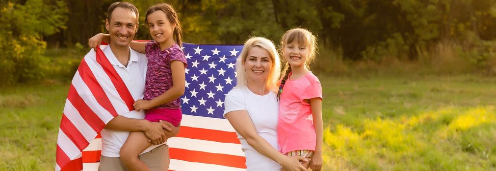 Happy family in field with USA, american flag on back