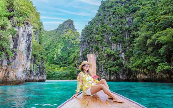 Asian women in front of a longtail boat at Kho Phi Phi Thailand, women in front of a boat at Pileh Lagoon