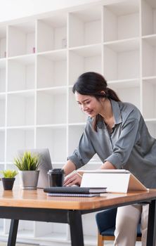 Portrait of a business woman standing working on a laptop in the office...