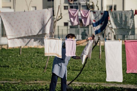 Woman tending clothes outside on a park in a neighbourhood in the coastal area of Janela. Espinho , Portugal 2023.