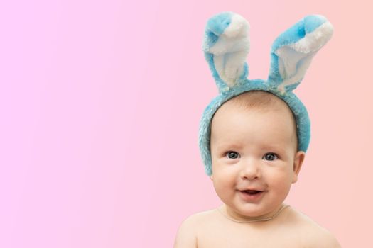 Cute funny baby with bunny ears on a colored background. Easter greeting card. Baby easter bunny.